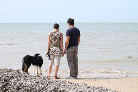 Happy couple contemplating the turquoise blue sea in a heavenly landscapeの写真素材