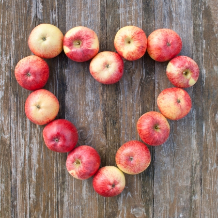 heart with red apples on a wooden tableの写真素材