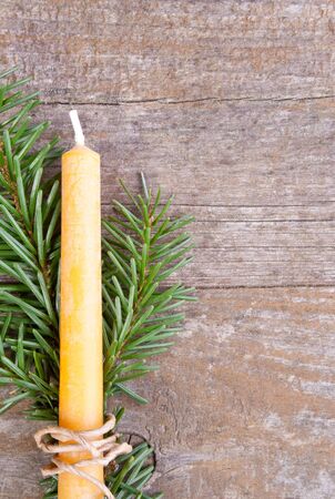 fir branch and yellow candle on wooden groundの写真素材