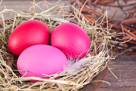 pink easter eggs in a nest on wooden groundの写真素材