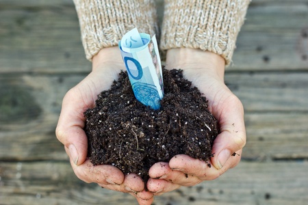 hands with garden soil and money