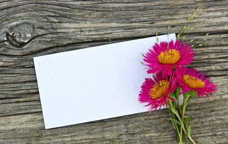pink flowers and white card on wooden table