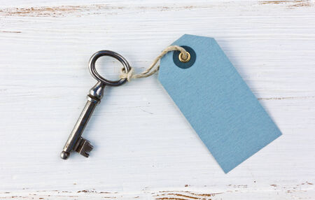 Old key and label on white wood