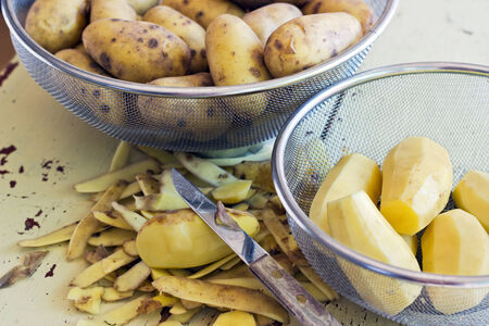 Sieve with yellow potatoes and knifeの写真素材
