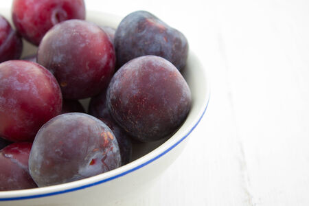 bowl with plums on a white tableの写真素材