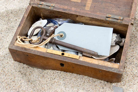 Wooden box with keys, pendants, stones and shells in beach sandの写真素材