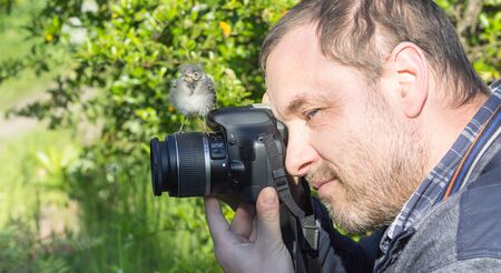 A photographer with a young songbird on his camera