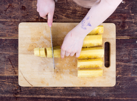 A girl is cutting a pineappleの写真素材