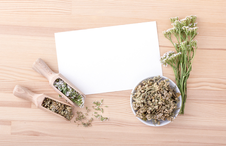 Top view of white card with copy space and fresh flowers and leaves on a wooden backgroundの写真素材