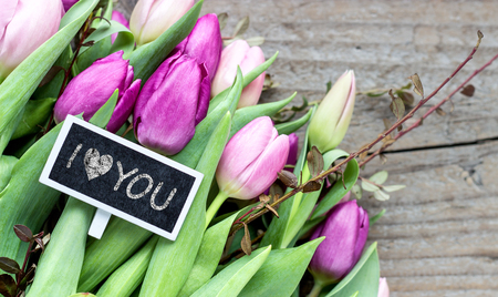 Bouquet with pink and purple tulips and small blackboard with the text: I love youの写真素材