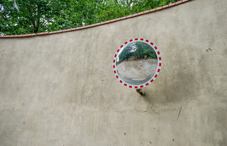 Wall in front of green trees with a round mirrorの写真素材