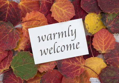 Card with colorful autumn leaves and English lettering: warmly welcome