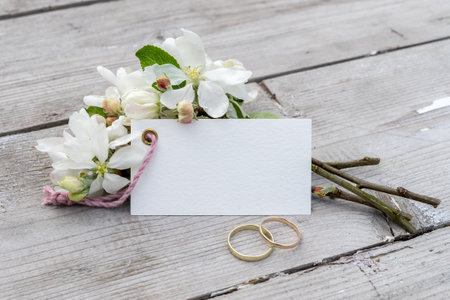 Wedding rings and a bouquet of spring flowers on a wooden backgroundの写真素材