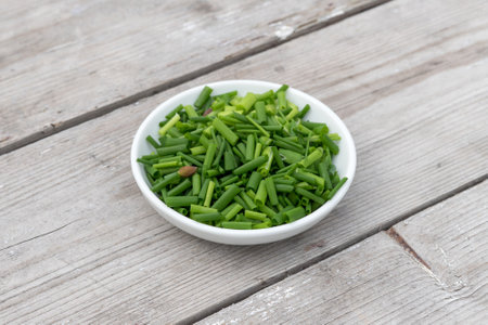 White bowl with sliced â€‹â€‹â€‹â€‹chives on a light wooden background