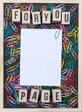 Black background with colorful paper clips, white copy space and wooden cubes with the text:...