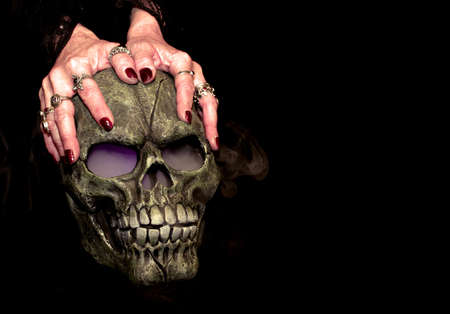A Halloween prop skull with fog coming from it's eyes and nose being held by a woman's hands.の写真素材