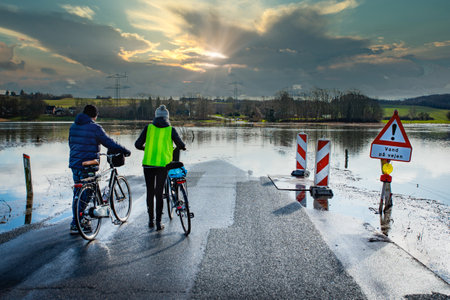 Cyclists on a flooded road in the countryside at sunset.の写真素材