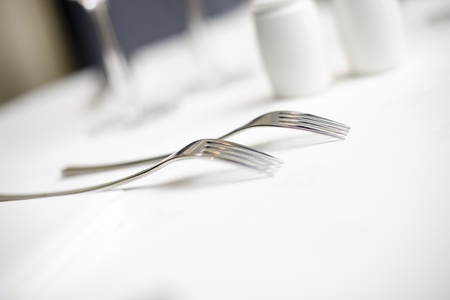 forks lined up on a white table cloth in a restaurantの写真素材