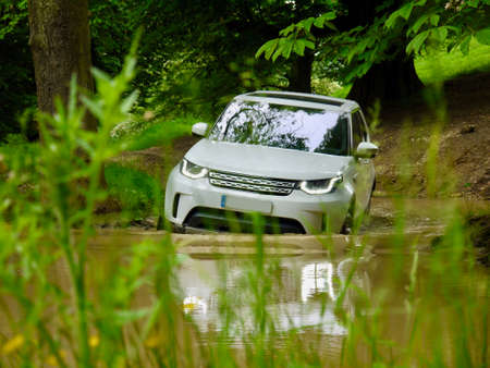 Luxury SUV 4x4 off-roading through a pond with all logos and numberplate removed.の写真素材