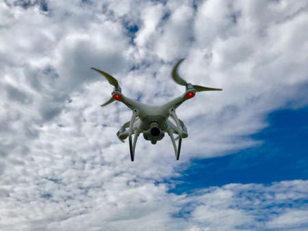 White Drone (quadcopter) With Blue Sky and Cloudsの写真素材