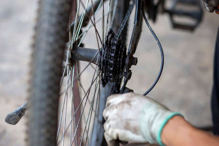 Close up The axle of the bicycle wheel is being drilled by the hands of a skilled practitioner, wearing protective gloves. Oil stains that add to the wheel bearings. Thai mechanicの写真素材