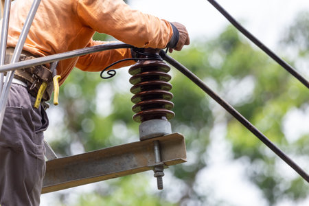 Rural electric poles are being repaired by electricians installing wires to connect. The tops of the...