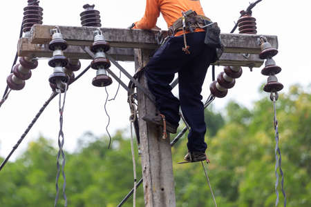 Rural electric poles are being repaired by electricians installing wires to connect. The tops of the...