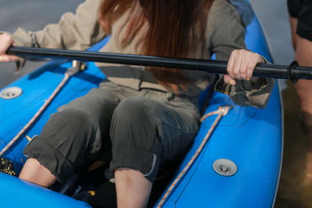 Close-up of a woman pulling a blue rubber boat to the shore.