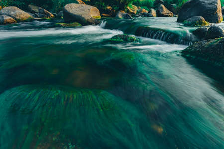 Clear water rapids with green moss grow on the rocks because of the drop in river water levels in the summer.の写真素材