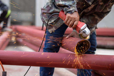 A large red iron pole Being welded by a welder On the construction site The iron was painted with red rust-proof paint.の写真素材