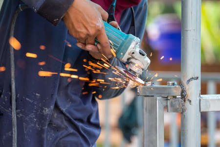 The welded iron fence is adorned with electric grinding wheels. There is a spark from the polishing. The job collection of the steel welderの写真素材