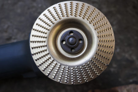 Close up of powerful, sharp, gold metal circular carving disc for an angle grinder. woodworking tool for shaping and grinding wood in professional workshop