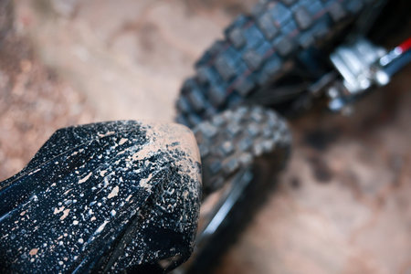 A close up of muddy off road motorcycle tire, black fender, dirt splashes, rugged tread, outdoor adventure, excitement, and dynamic movement in natural terrain