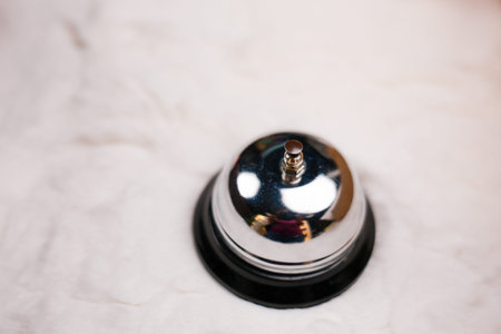 Shiny silver service bell resting on bright marble hotel reception desk presenting welcoming hospitality ready to alert staff for prompt customer assistance