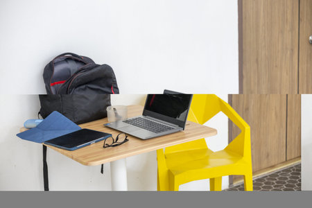 A backpack and laptop on small wood desk with tablet, glasses and cup creating casual study workspace with bright yellow chair and minimal interior mood