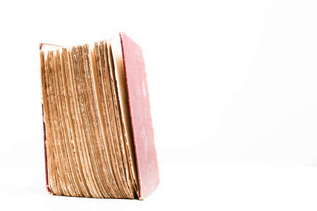 Large old hardback book slightly open, showing worn pages inside, isolated on a white background