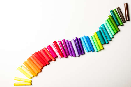Wave of rainbow coloured pen lids isolated on a white background