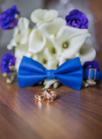 Wedding rings and the bride's bouquet on a wooden tableの写真素材