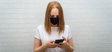 beautiful girl in a black medical mask with a phoneの写真素材