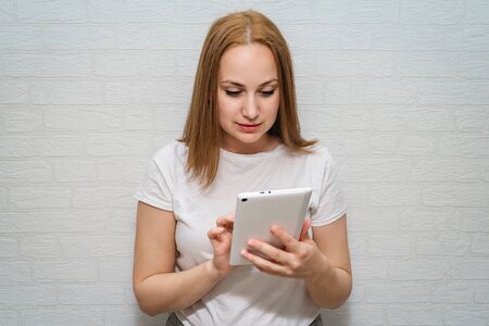 Beautiful girl reads the news about the virus in a white tablet