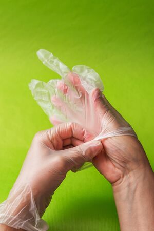 Close up of female doctor hand wearing sterile glove. on a green backgroundの写真素材