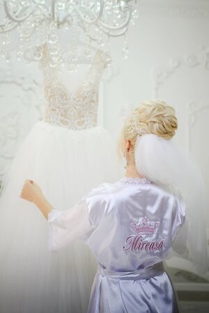 Attractive bride in white dress, touches the wedding dress on the mannequin in wedding morning. Trendy wedding style shot. Bride touch your white wedding dress. Fashion brideの写真素材
