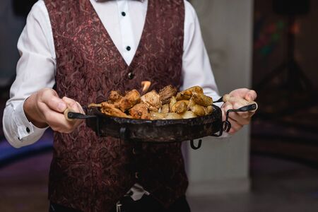 Waiter's hands hold national Moldavian dish with meat and potatoes. close-upの写真素材
