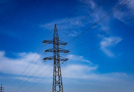 power grid pylon against blue cloudy sky.の写真素材