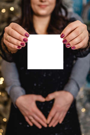 A guy and a pregnant girl hug and make a heart on her tummy with their own hands. Valentines day, holiday concept - family, couple, man and woman, love, pregnancy.の写真素材