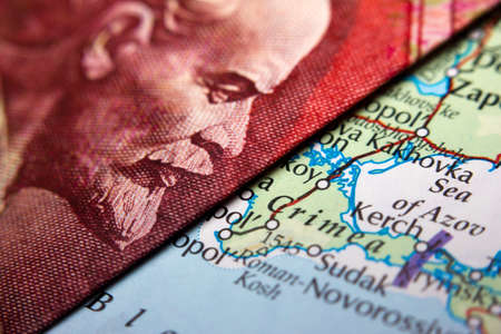 An antique map showing Crimea in between a close-up of a Russian ruble banknote - figuring Lenin - and a 10 US dollar banknoteの写真素材
