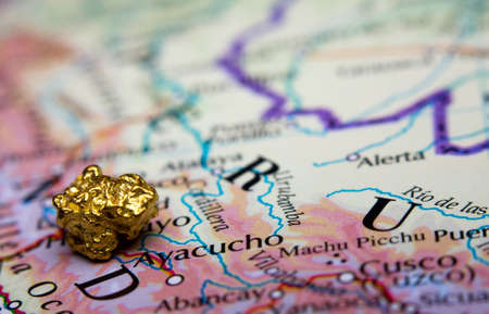 Close-up of a gold-nugget on top of a map of Peruの写真素材