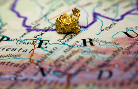 Close-up of a gold-nugget on top of a map of Peruの写真素材