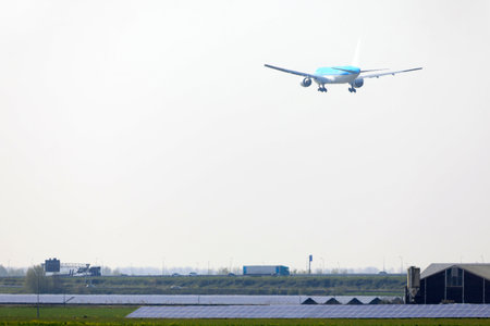A plane descending over a field with solar panelsの写真素材
