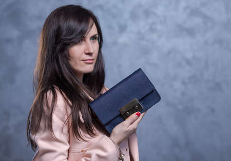 Positive emotional portrait of young and pretty girl. Portrait of beautiful woman holding a stylish clatch. Bags accessories advertising conceptの写真素材